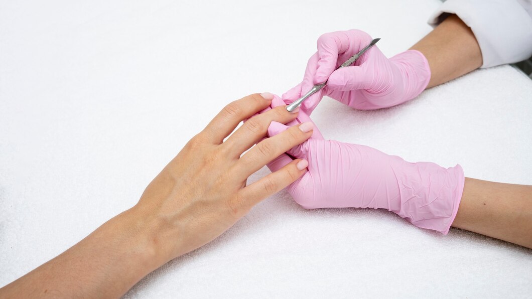 Nail technician wearing pink nitrile gloves while performing a manicure or pedicure